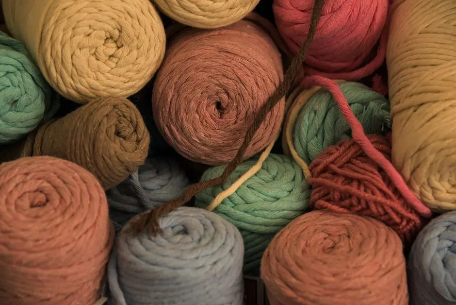 Peralatan menyulam dan benang katun warna pastel di atas meja kayu